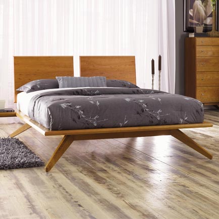 Modern wooden bed with grey floral duvet.