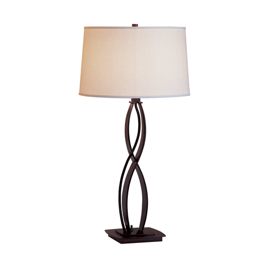 Hubbardton Forge Almost Infinity Table Lamp featuring a twisted dark brown metal base and white fabric shade.