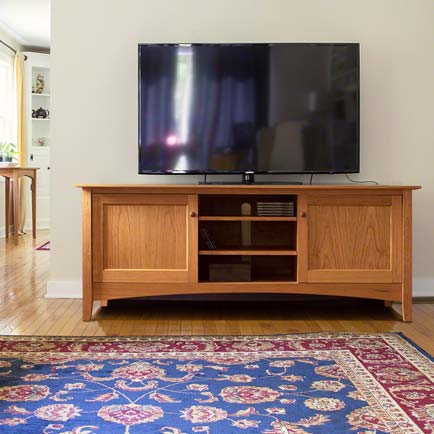 A tv stand in a living room with a blue rug.