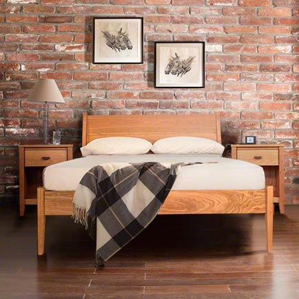 A wooden bed with a brick wall behind it.