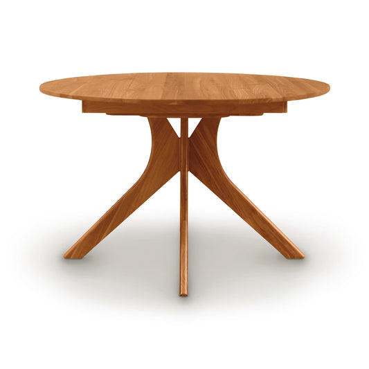 Audrey Round Extension Dining Table by Copeland Furniture with a solid wood top and distinctive geometric base, showcasing elegant American craftsmanship.