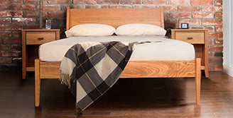 A wooden bed in a room with a brick wall.