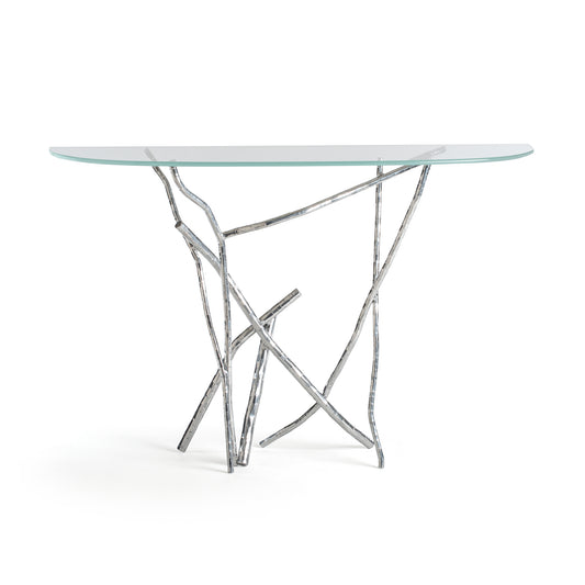 Brindille Console Table by Hubbardton Forge with clear glass top and unique abstract metal base in silver finish, showcasing exquisite craftsmanship.