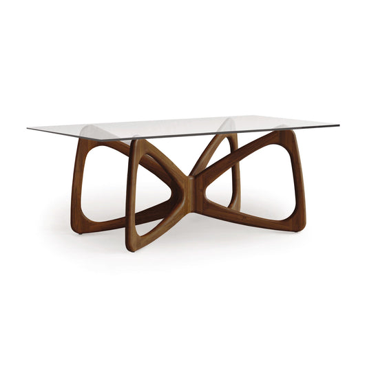 Butterfly Glass Top Dining Table by Copeland Furniture with a sculptural hardwood base and gracefully curved intersecting legs.