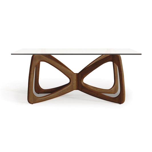 Copeland Butterfly Glass Top Dining Table featuring a rectangular clear glass surface and an elegant, sculptural hardwood base.