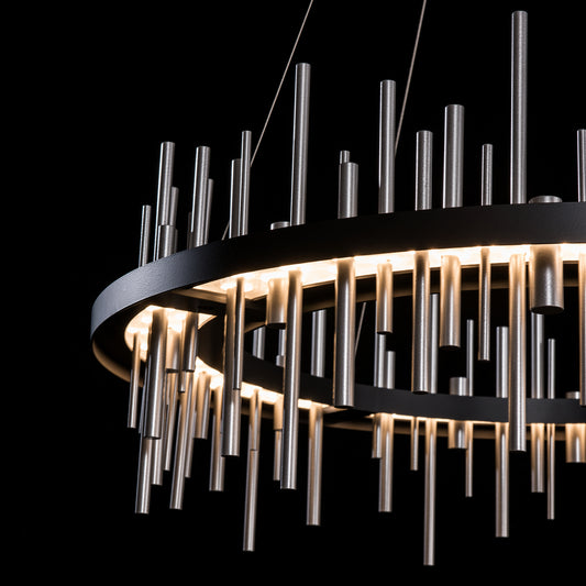Hubbardton Forge Circular Cityscape Pendant featuring cylindrical metal rods with a glowing finish.