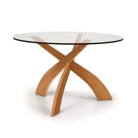 Entwine Round Glass Top Dining Table by Copeland Furniture with a sleek tempered glass surface and three sculptural interlocking cherry wood legs.