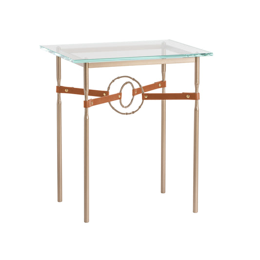 Elegant Hubbardton Forge Equus Side Table emphasizing American craftsmanship with a glass top, gold metal legs, and unique gold circle design.