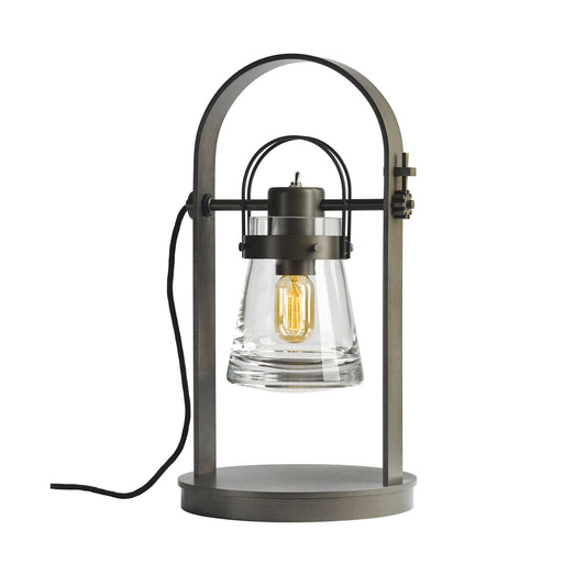 Erlenmeyer Table Lamp by Hubbardton Forge, featuring a metal lantern-style with visible bulb and clear glass shade, showcasing a steampunk design.