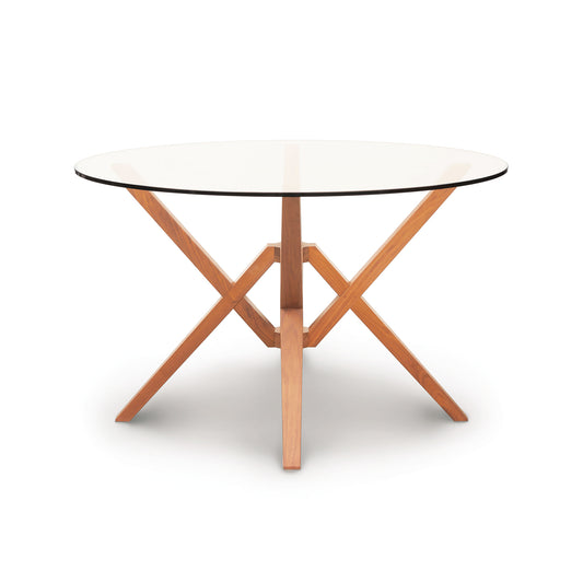 Copeland Furniture Exeter Round Glass Top Table with sculptural geometric hardwood base, showcasing modern craftsmanship and elegant design.