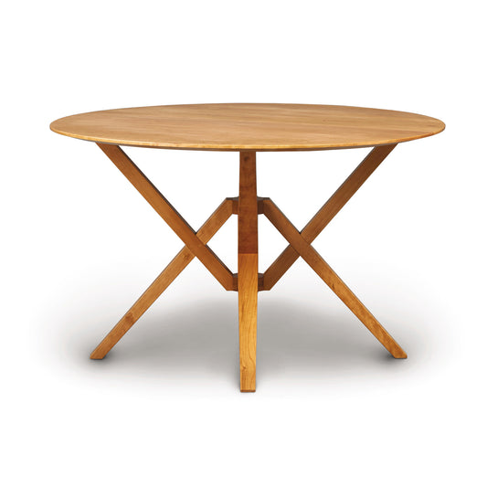 Exeter Round Solid Top Dining Table by Copeland Furniture with striking angular legs and natural hardwood craftsmanship, highlighted in detail.