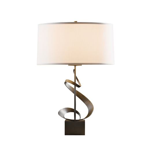 Hubbardton Forge Spiral Table Lamp with white cylindrical shade and metal base showcasing a detailed spiral design on a square foundation.