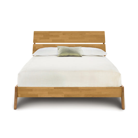 Modern and sustainable Linn Platform Bed by Copeland Furniture with white bedding and a green cushion.