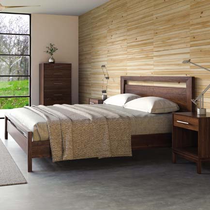 Wooden bed with gray bedding, accompanied by two nightstands and a tall dresser.