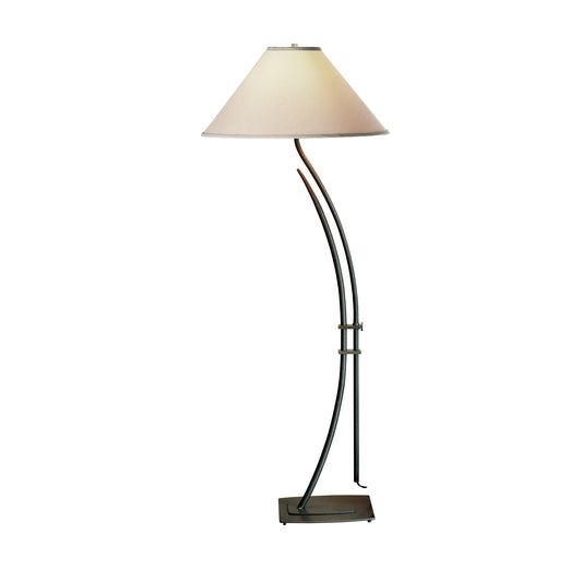 Hubbardton Forge Metamorphic floor lamp with beige conical shade and artisan-crafted metallic stand.
