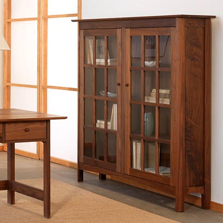A wooden bookcase in a room with a desk.