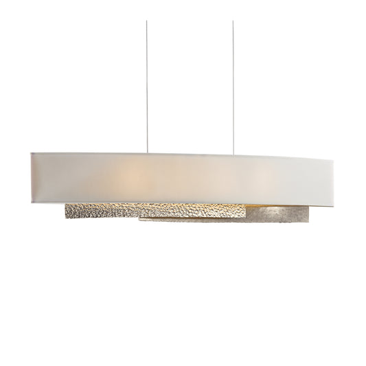 Hubbardton Forge Oceanus Pendant showcasing a handmade oval white shade with textured metallic accents, suspended by slim cables.
