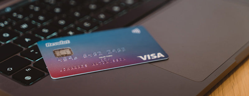 A credit card sitting on top of a laptop.