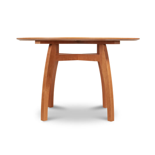 Vermont Modern Round Solid Top Pedestal Table by Lyndon Furniture with four curved legs and natural wood finish, highlighting elegant craftsmanship.