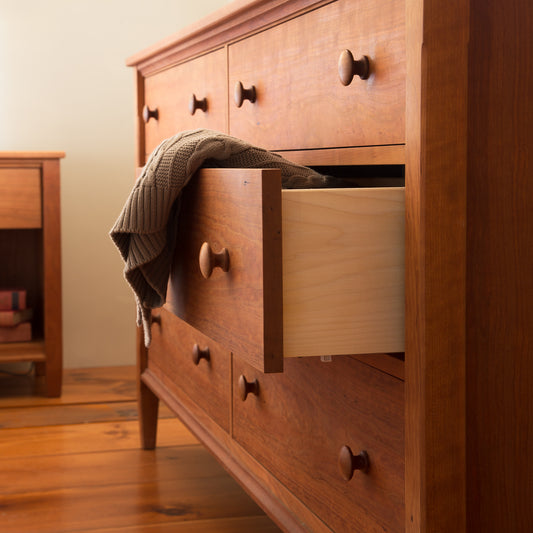 Vermont Shaker 6-Drawer Dresser by Maple Corner Woodworks showcasing exquisite craftsmanship with an open drawer and a brown knitted sweater.